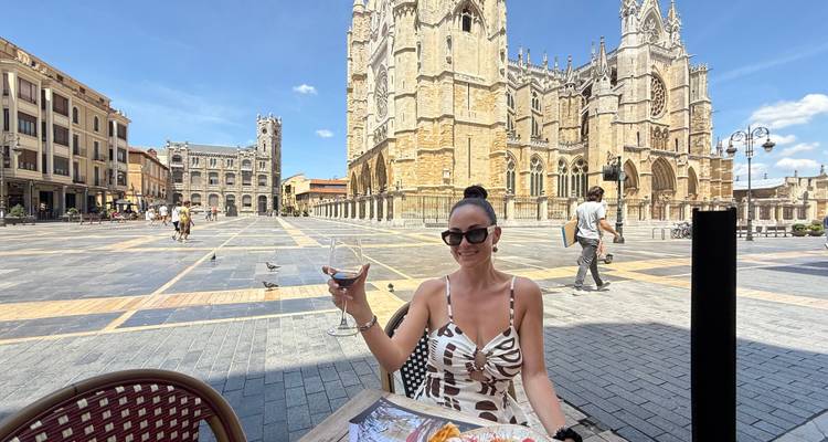 Femme dînant en plein air avec une cathédrale majestueuse en arrière-plan.