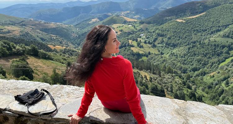 Femme profitant d'une vue panoramique sur des collines et vallées ondulantes.