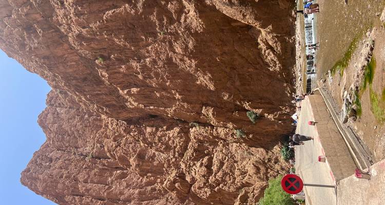 Hautes falaises avec des gens marchant près d'une rivière.