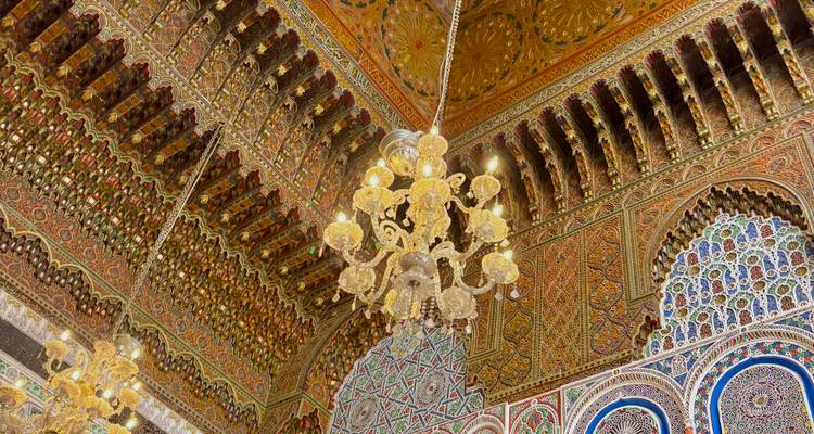 Plafond orné de décorations avec des lustres dans un bâtiment historique.