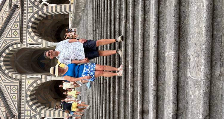 Two people standing on the steps in front of a cathedral.