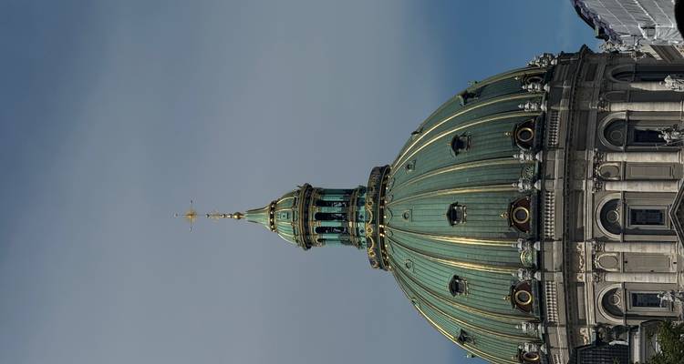 Bâtiment au dôme vert contre un ciel bleu.