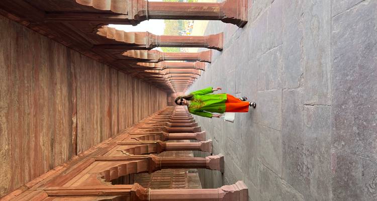 Mujer caminando por un pasillo histórico con arcos.