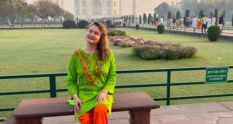 Femme assise sur un banc avec le Taj Mahal en arrière-plan.