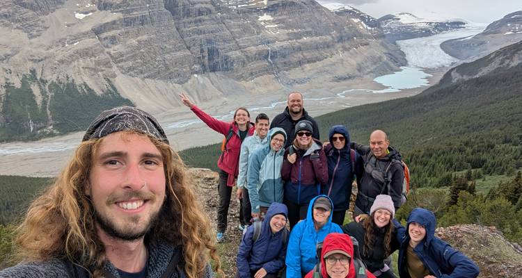 Groupe de randonneurs posant avec un paysage montagneux en arrière-plan.