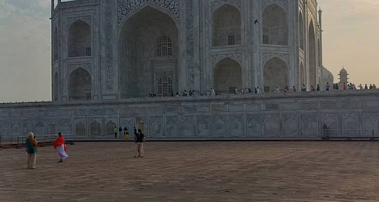 Vue de côté du Taj Mahal avec des personnes en tenue colorée au premier plan.