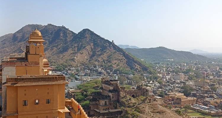 Vue aérienne d'un complexe fortifié avec des collines et une ville en contrebas.
