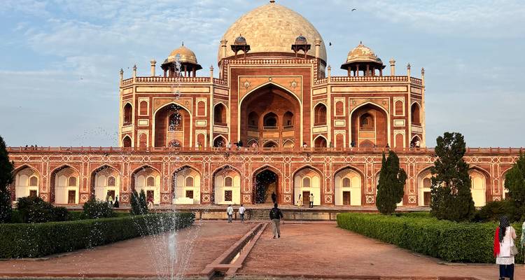 Humayun's Tomb with fountain and people walking in the garden area.