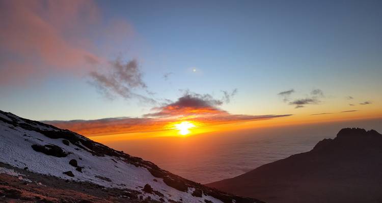 Beautiful sunrise view from a mountain with snowy peaks and clouds.