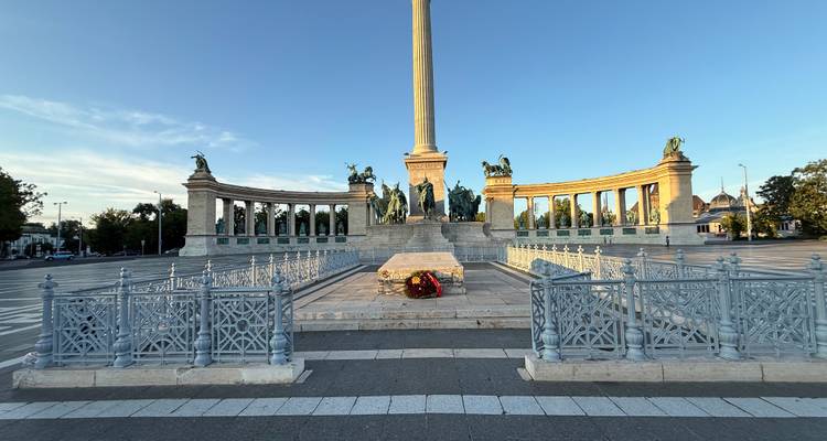 Place des Héros avec de grandes statues et une haute colonne.