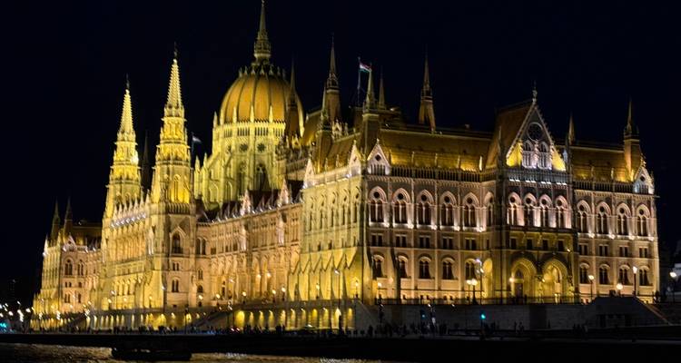 Vue illuminée d'un grand bâtiment le long de la rivière la nuit.