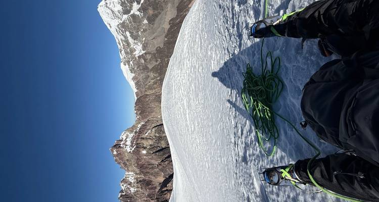 Paysage de montagne enneigée avec du matériel d'alpinisme au premier plan.