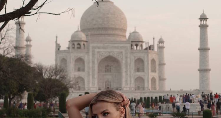 Femme posant devant le Taj Mahal par une journée claire.