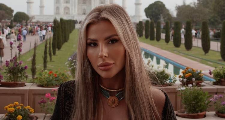 Une personne avec le Taj Mahal en arrière-plan, entourée de jardins.