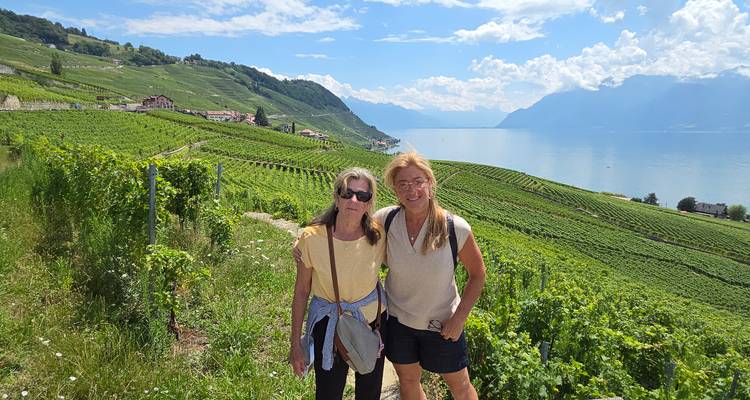 Two women posing in a vineyard with a lake view