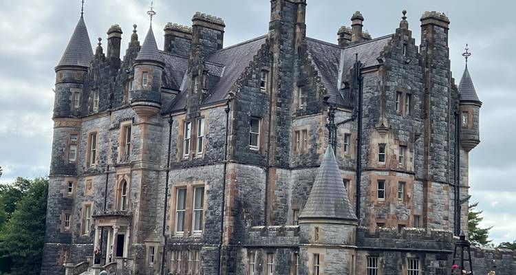 Imposantes Schloss im gotischen Stil mit mehreren Türmchen und detaillierter Steinmetzarbeit.