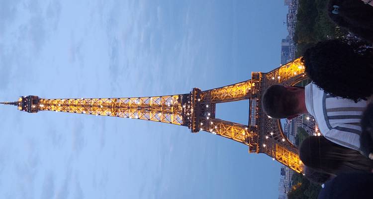 La Torre Eiffel iluminada por la noche con una multitud abajo.