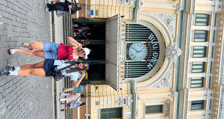 Two people posing in front of the Saigon Central Post Office.