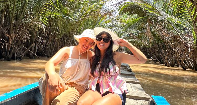 Two people on a boat cruising through Mekong Delta.