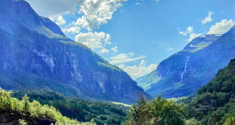 Mountainous landscape with lush trees and a clear sky.