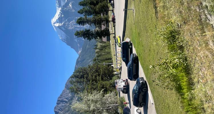 Une zone de stationnement avec des voitures et une montagne enneigée en arrière-plan.