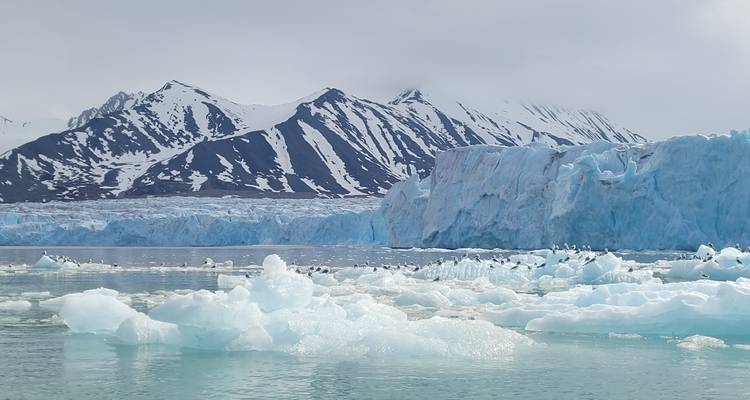 Glacier with stunning icy formations in front of mountainous terrain in Svalbard, Norway.