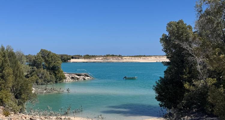 A calm bay with turquoise water and a boat.