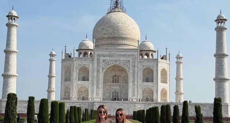 Two people standing in front of the Taj Mahal on a clear day.