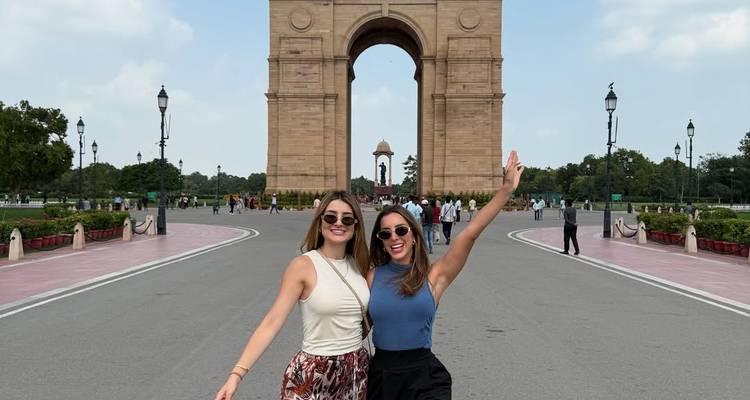 Two people posing in front of India Gate, a large archway in New Delhi.