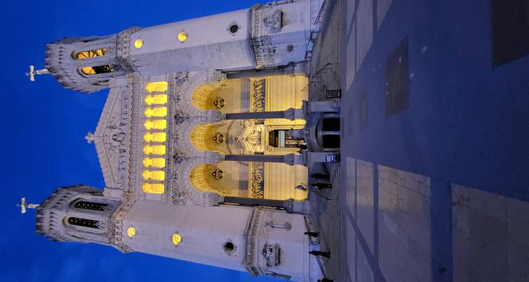 Illuminated basilica with intricate architecture during blue hour.
