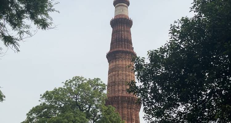 Tall red sandstone tower among trees.