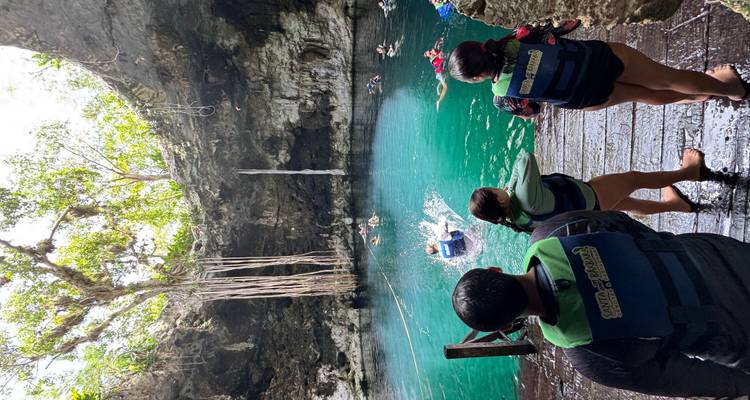 Un cénote avec de l'eau bleue claire et des personnes se préparant à nager.