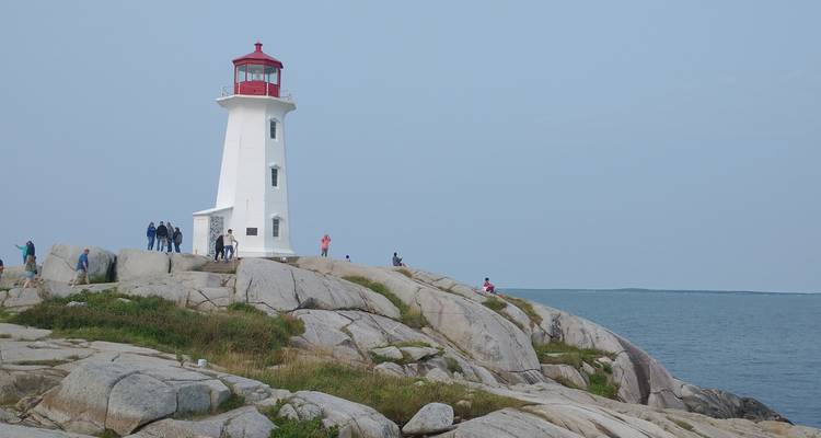 Iconic lighthouse on rocky coastline with people exploring.