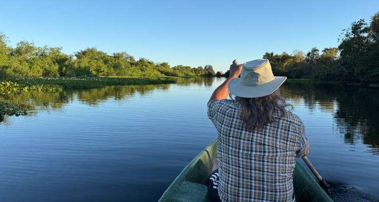 Homme assis dans un bateau sur une rivière calme.