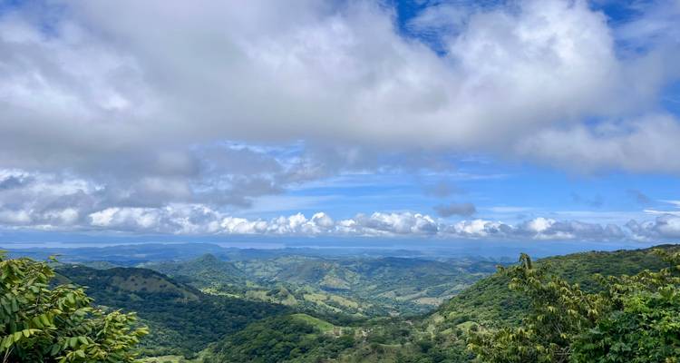 Expansive view of green hills and blue sky with clouds.
