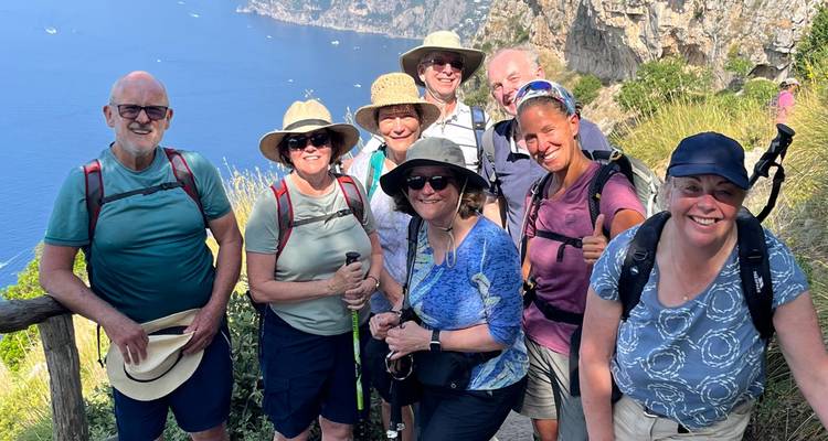 Group of hikers posing with a seaside view in the background.