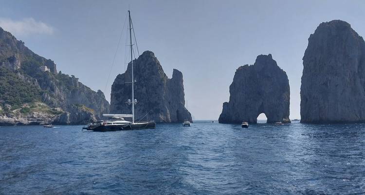 Boats in the sea with dramatic rock formations.