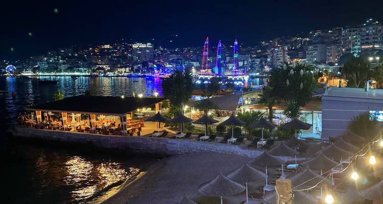Night view of a vibrant seaside city with illuminated buildings.
