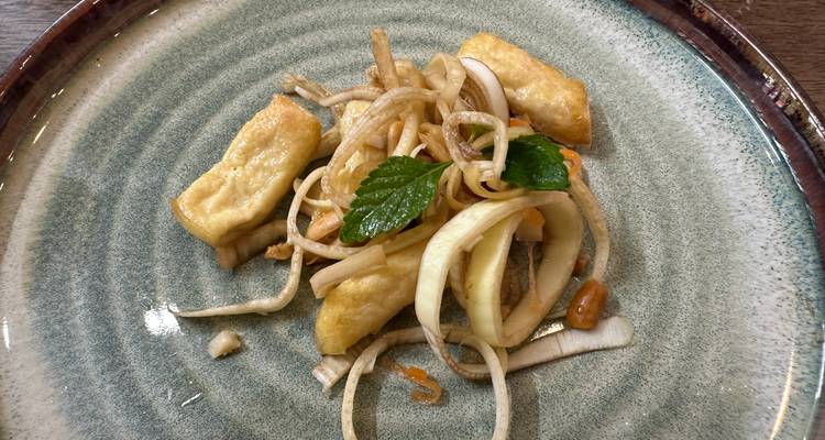 Un plat avec du tofu frit et une salade de nouilles dans une assiette.