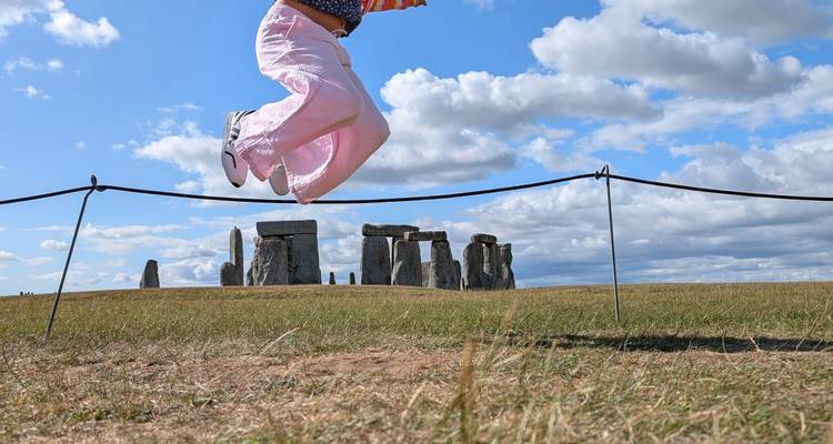 Une personne sautant près du monument historique de Stonehenge.