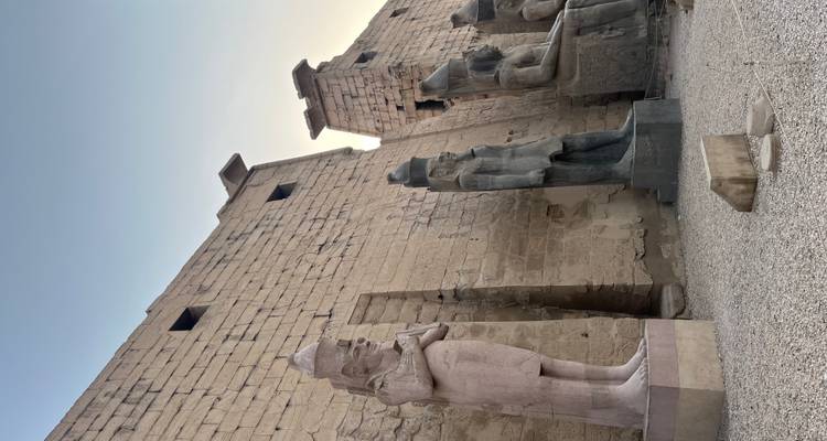 Ancient Egyptian statues and temple walls at sunset.