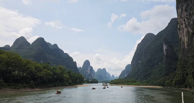 River with boats and karst mountains under a blue sky.