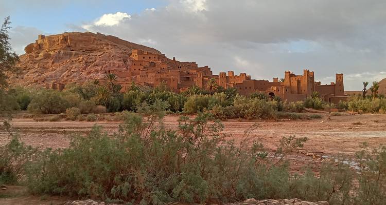 Vista de una Kasbah tradicional con palmeras y una colina.