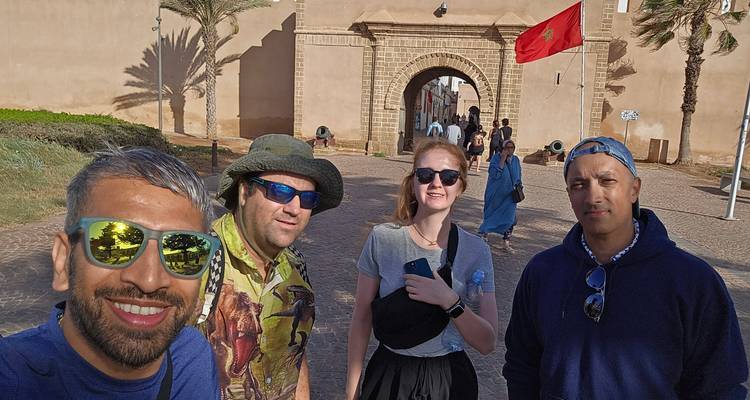 Grupo de turistas tomándose una selfie en una puerta histórica con una bandera marroquí.