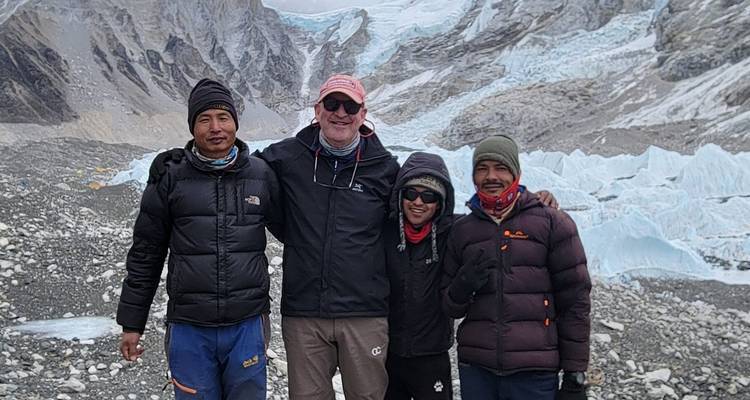 Quatre personnes posent au camp de base d'une montagne enneigée.