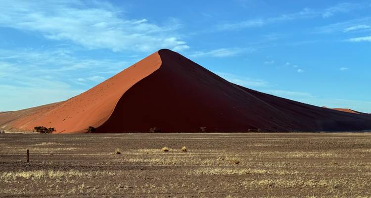 Dune de sable rouge sous un ciel bleu dégagé.
