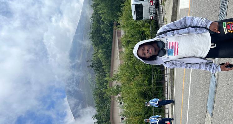 Persoon die voor de berg Fuji staat, omringd door groen.