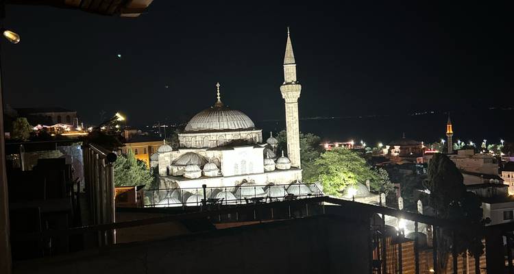 Vue nocturne d'une mosquée éclairée dans un paysage urbain turc.
