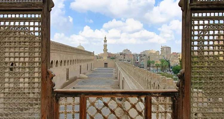 Vue du Caire depuis une fenêtre décorative avec horizon et coupoles.