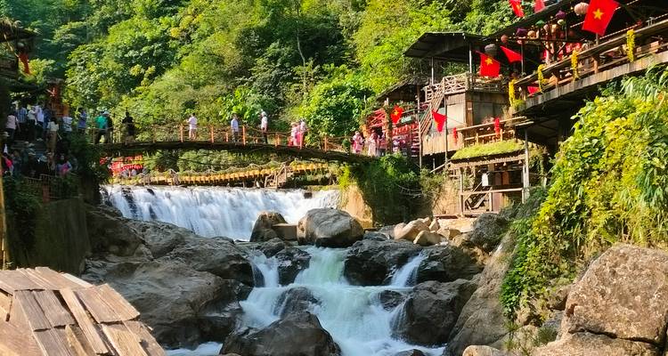 Scène idyllique d'une cascade avec un pont et des touristes.